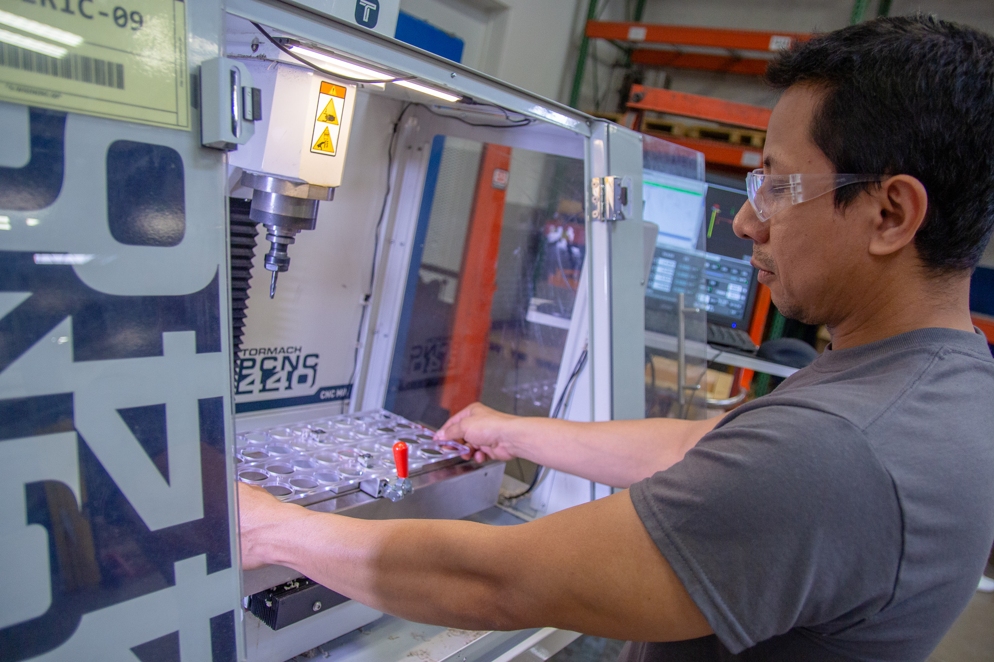An operator places an injection molded part into CNC mill for finishing